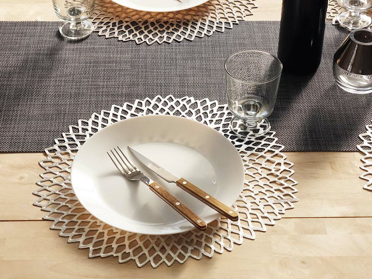 発色のよいシルバーでダリアの花を模ったのチルウィッチの円形ランチョンマットとダークグレーの平織りのテーブルランナーでコーディネートした食卓