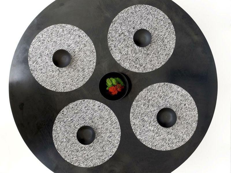 黒のラウンドテーブルに合わせたチルウィッチの丸型のランチョンマットの中で最もラグジュアリーなレースの繊細さと金属光沢を兼ね備えたシルバーのデザイン