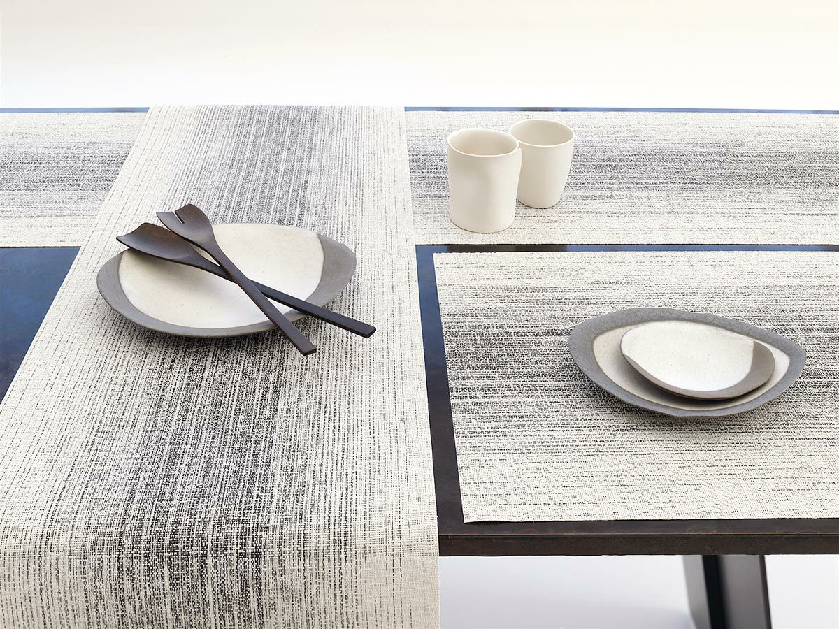 黒色のテーブルに合わせたアイボリーとチャコールグレイの絣のグラデーションのランチョンマットとテーブルランナー