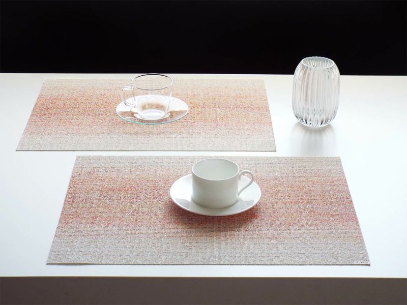白のテーブルに合わせたピンクとオレンジとホワイトの絣のグラデーションのランチョンマットとカップ＆ソーサー