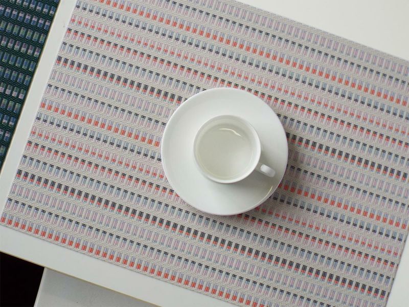 オフホワイトのベースにオレンジ・ピンク・ブルーの刺繍模様をあしらったランチョンマット